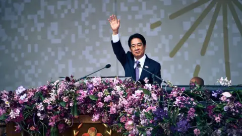 Getty Images William Lai, de terno, balança o braço em direção à multidão enquanto está no palco