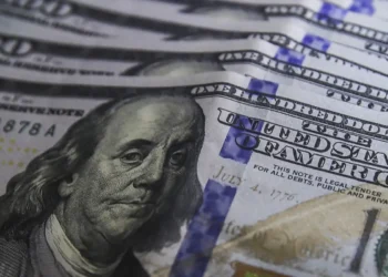 Cédulas de dólar e moedas de real, símbolo da variação cambial