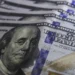 Cédulas de dólar e moedas de real, símbolo da variação cambial